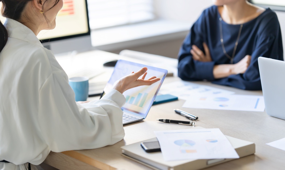 資料やチャートを用いて打ち合わせをする様子。マーケティングコンサルのイメージ